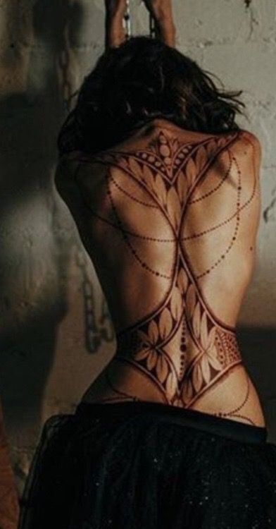 the back of a woman's body with intricate tattoos on her upper and lower back