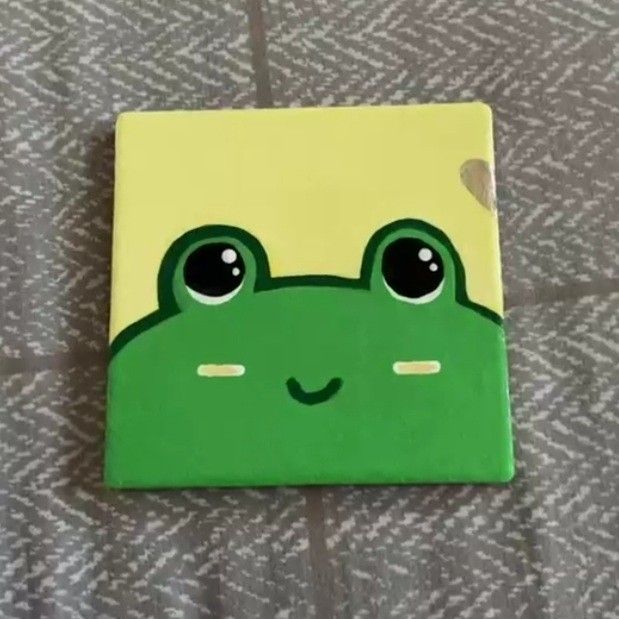 a green frog with big eyes sitting on top of a bed