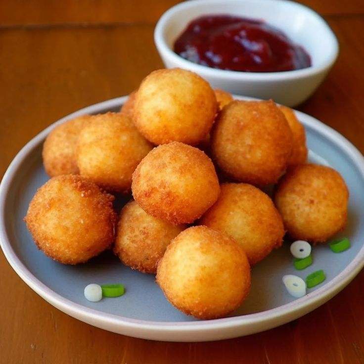 some fried food is on a plate next to a small bowl of ketchup