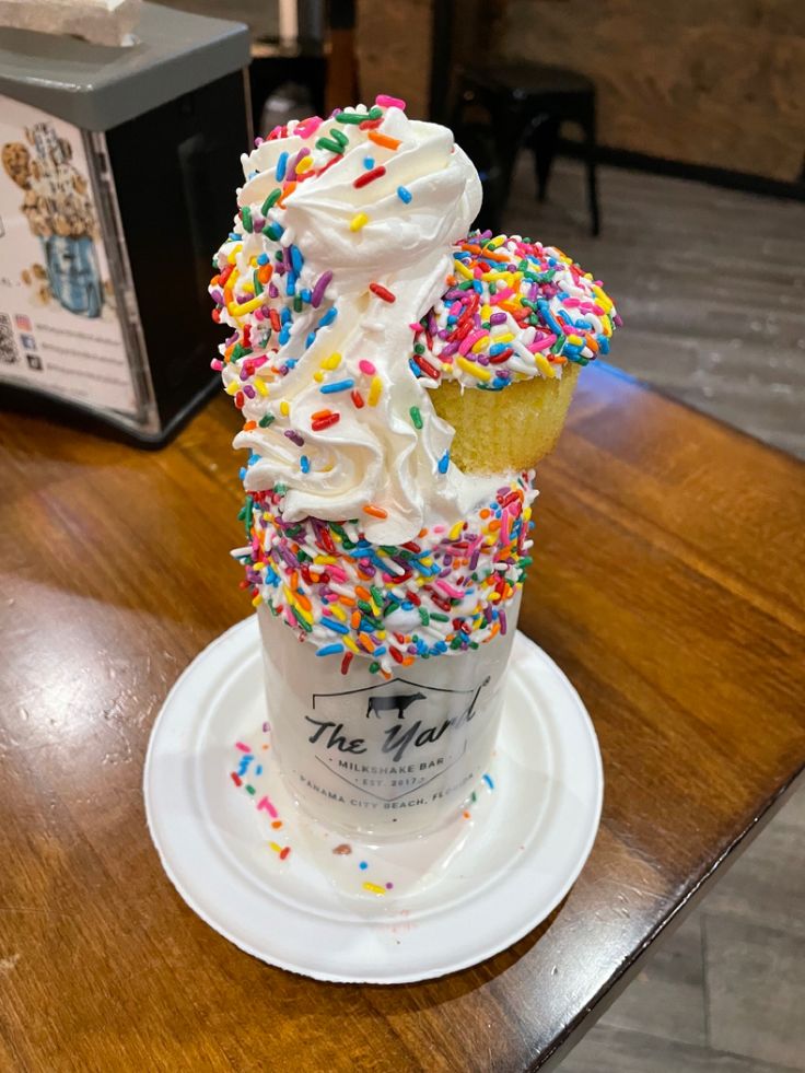 an ice cream sundae with sprinkles is on a white saucer