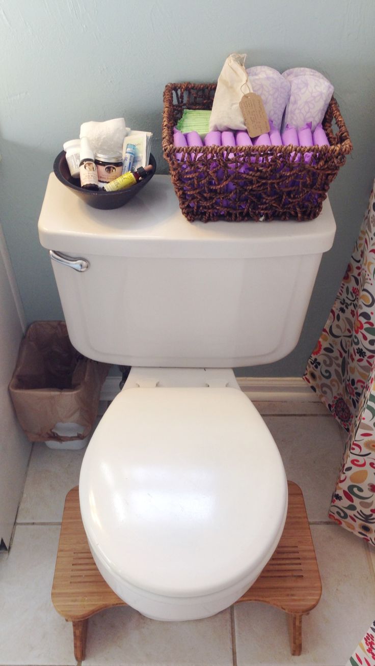 a white toilet sitting in a bathroom next to a basket filled with towels and other items