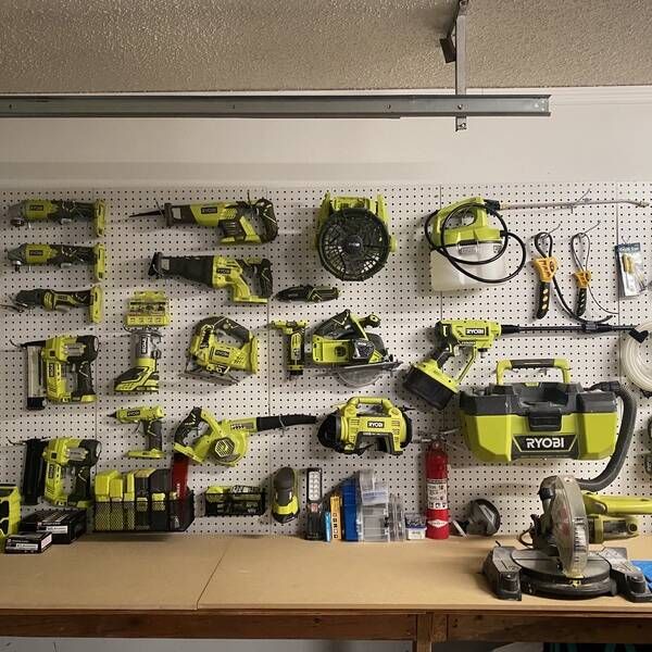 a workbench with many tools on the wall and pegs attached to it