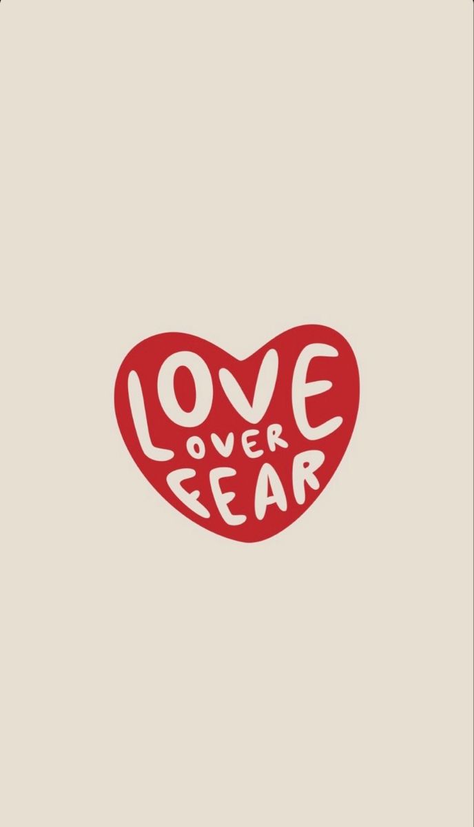 a red heart with the words love over fear written in white ink on a beige background