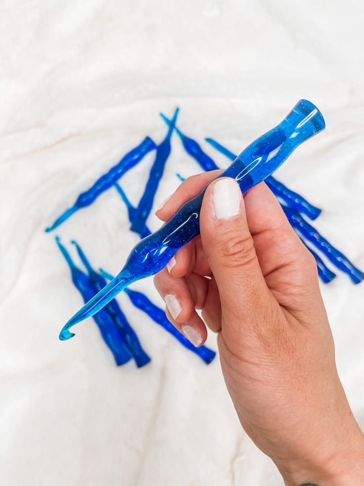 a person holding a blue plastic object in their left hand and writing on the paper