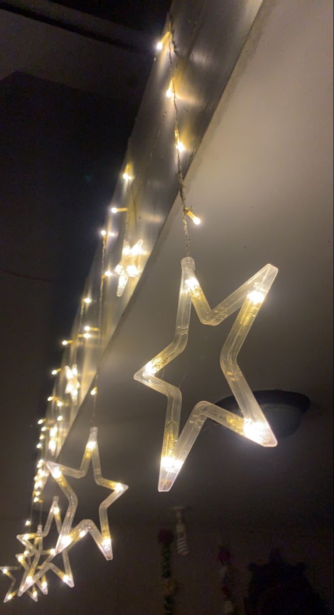 some lights are hanging from the ceiling in front of a star shaped light fixture with stars on it