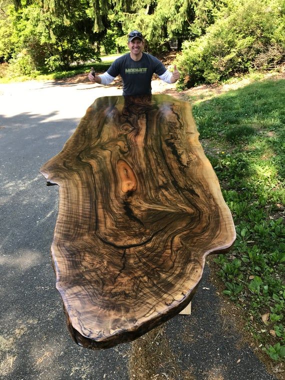 a man standing on top of a large wooden table in the middle of a road