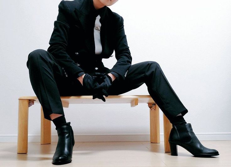 a man sitting on top of a wooden bench wearing black shoes and a white shirt