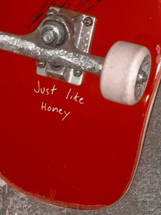 a red skateboard with the words just like honey written on it's side