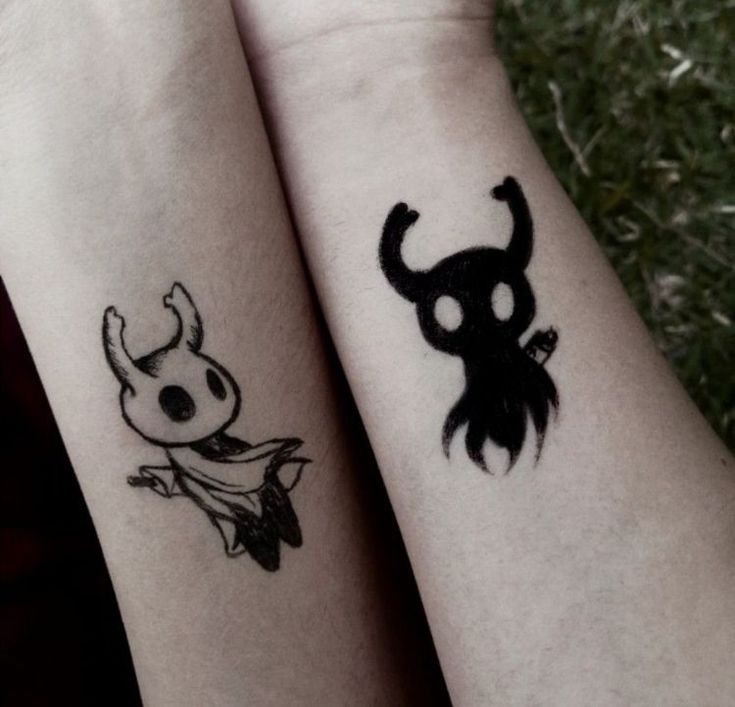 two people with matching tattoos on their arms, one has a skull and the other has a devil