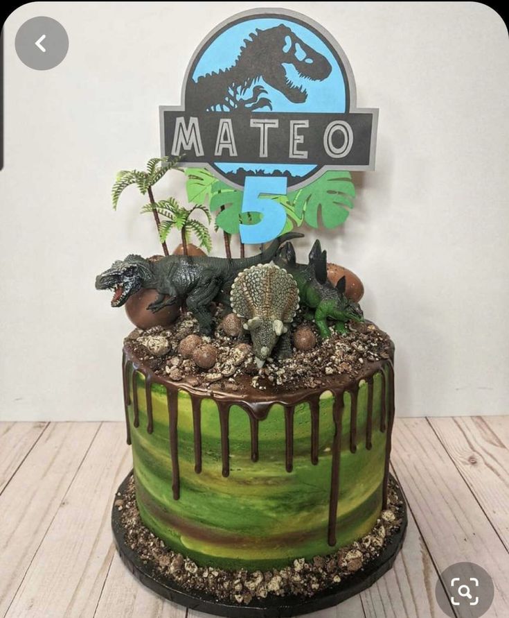 a dinosaur themed cake with chocolate icing and fondant on the top that says mateo