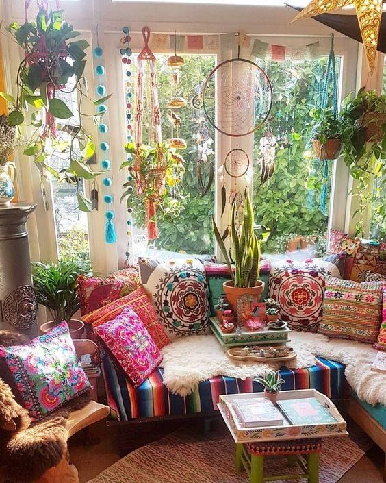 a living room filled with lots of colorful pillows and furniture in front of a window