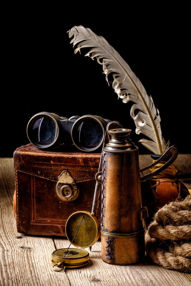 an old leather case with a feather quill, binoculars and other items on it