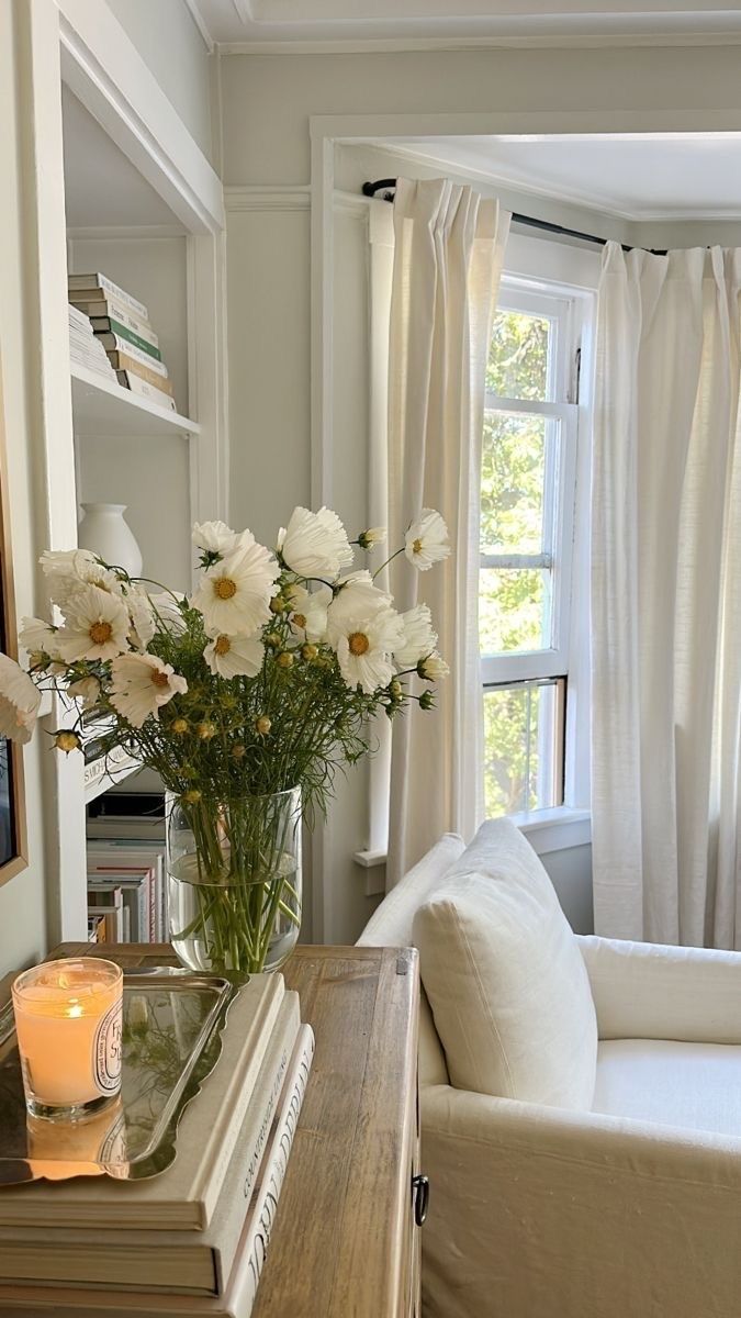 a living room filled with furniture and a vase full of flowers on top of a table