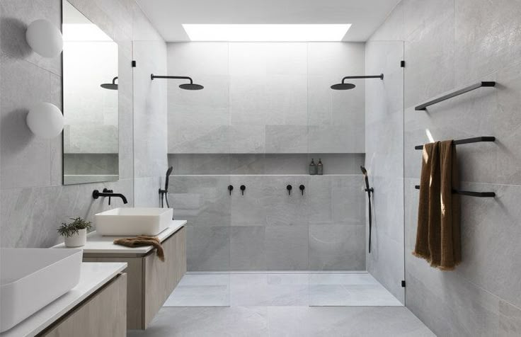 a white bathroom with two sinks, mirrors and towel racks on the wall next to it