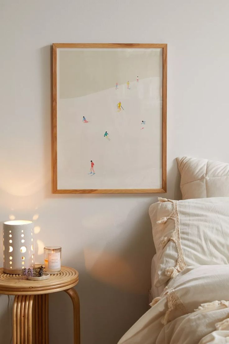 a bed with white sheets and pillows next to a painting on the wall above it