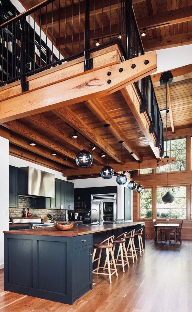 an open kitchen and dining area with wooden floors, high ceilings, and large windows