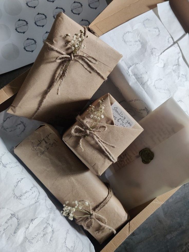 three wrapped presents sitting on top of each other next to a white envelope and brown ribbon