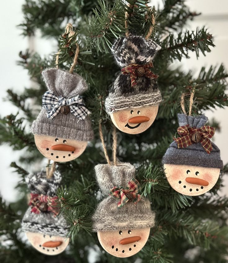 four snowman ornaments hanging from a christmas tree