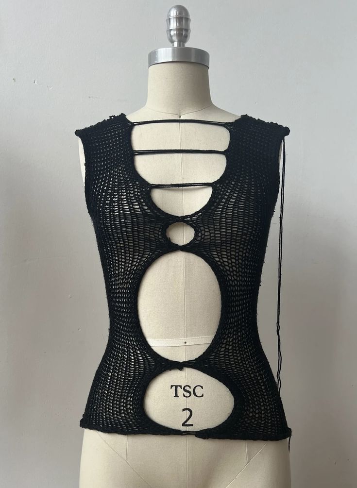 a mannequin wearing a black top with three circles on the front and bottom