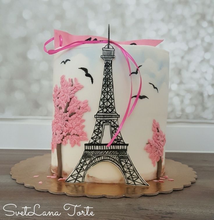 a cake with the eiffel tower painted on it's side and pink ribbon