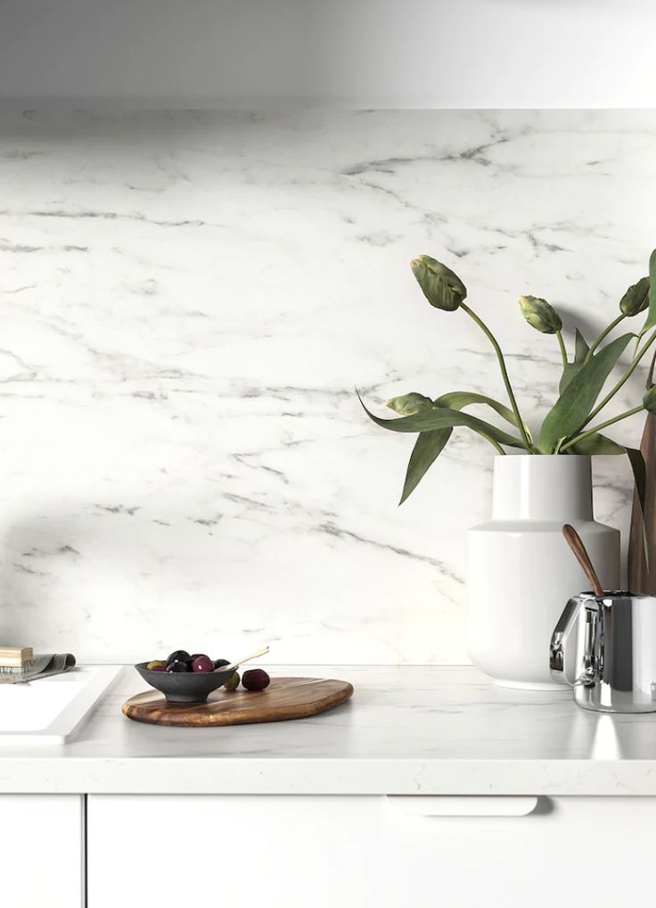 a white marble kitchen counter top next to a cutting board and potted plant on it