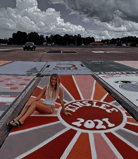 a woman sitting on the ground in front of a sign