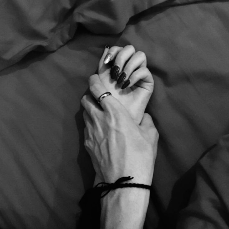 a woman's hand resting on the edge of a bed with her black and white nails