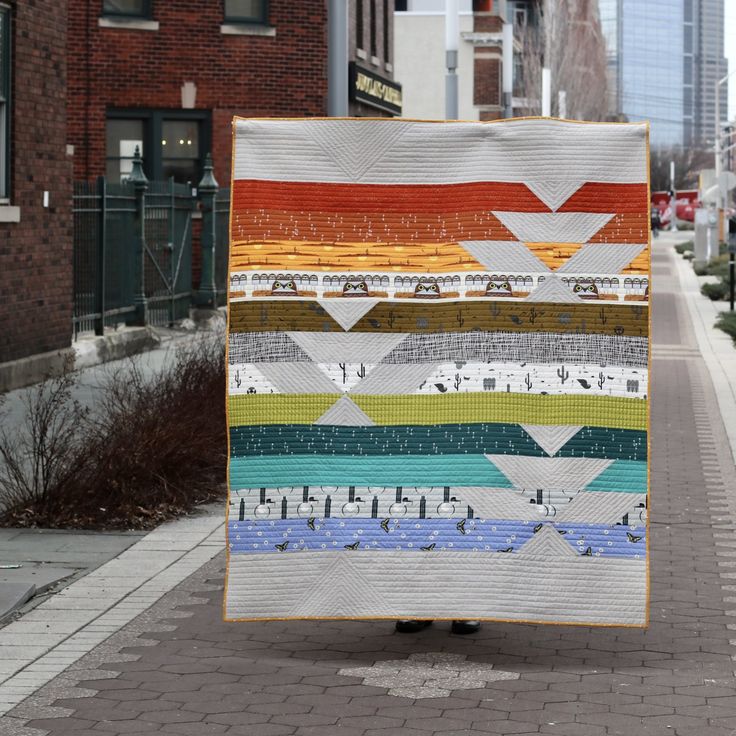 a person is walking down the street with a quilt