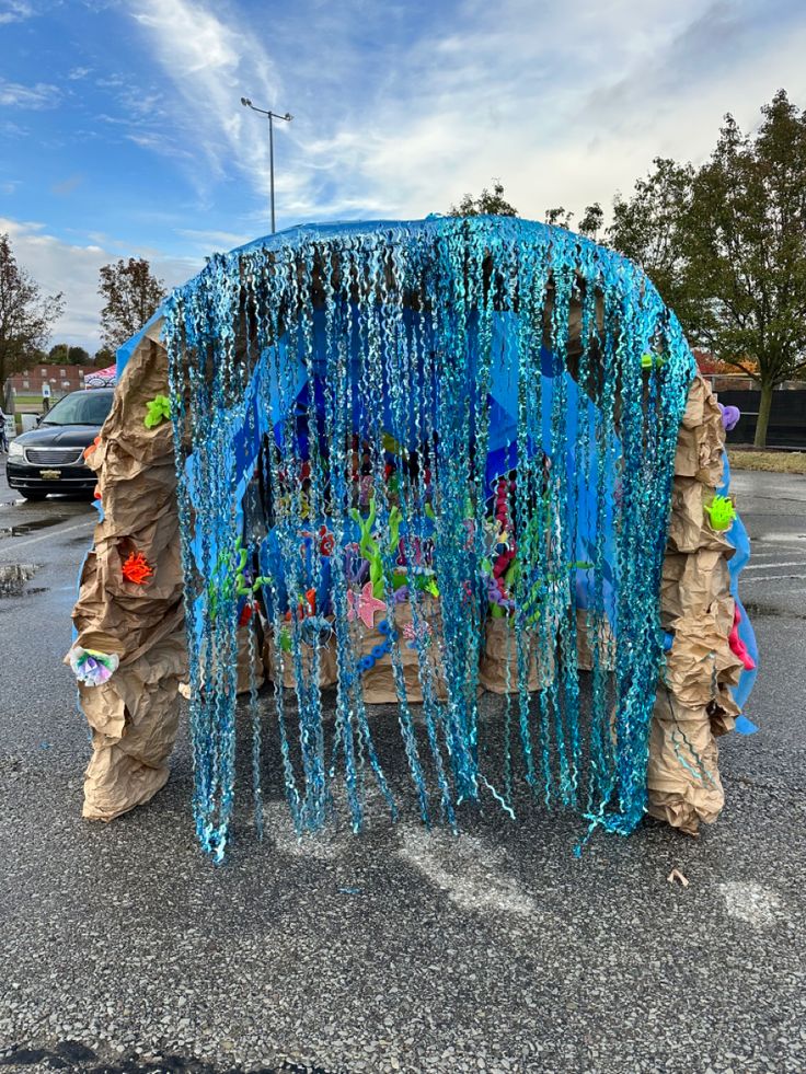 an elephant made out of plastic beads and streamers on the side of a road