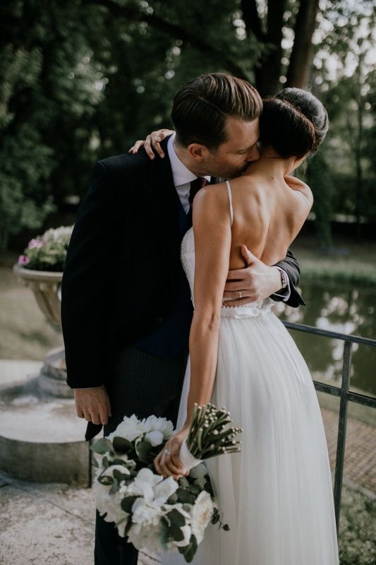 a bride and groom kissing in front of a pond