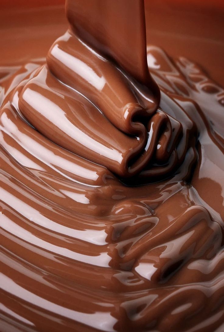 melted chocolate in a bowl with a spoon sticking out of the top and flowing down