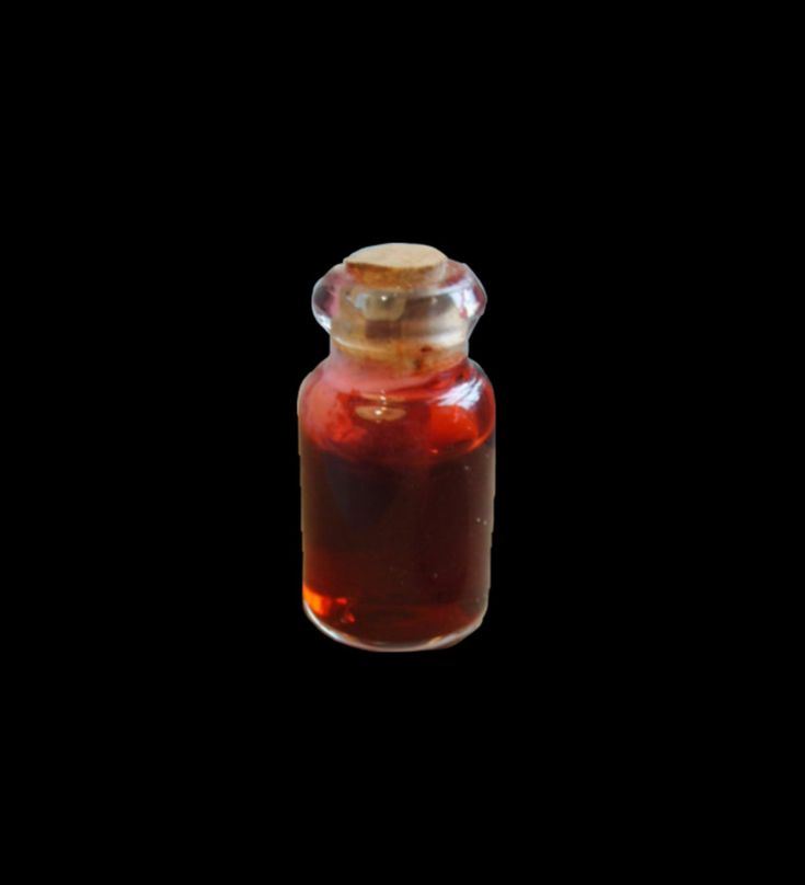 a glass jar filled with liquid on top of a black surface and a gold lid