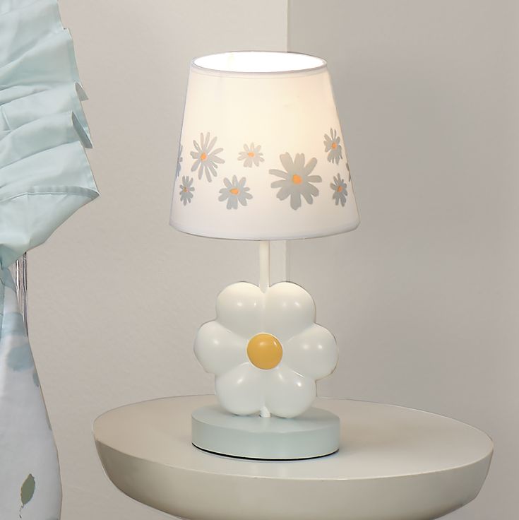 a white lamp sitting on top of a table next to a vase with flowers in it