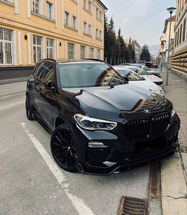 a black bmw suv parked in front of a building