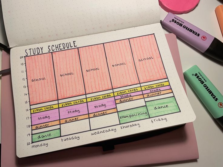 a notebook with a school schedule on it next to some markers and pencils,