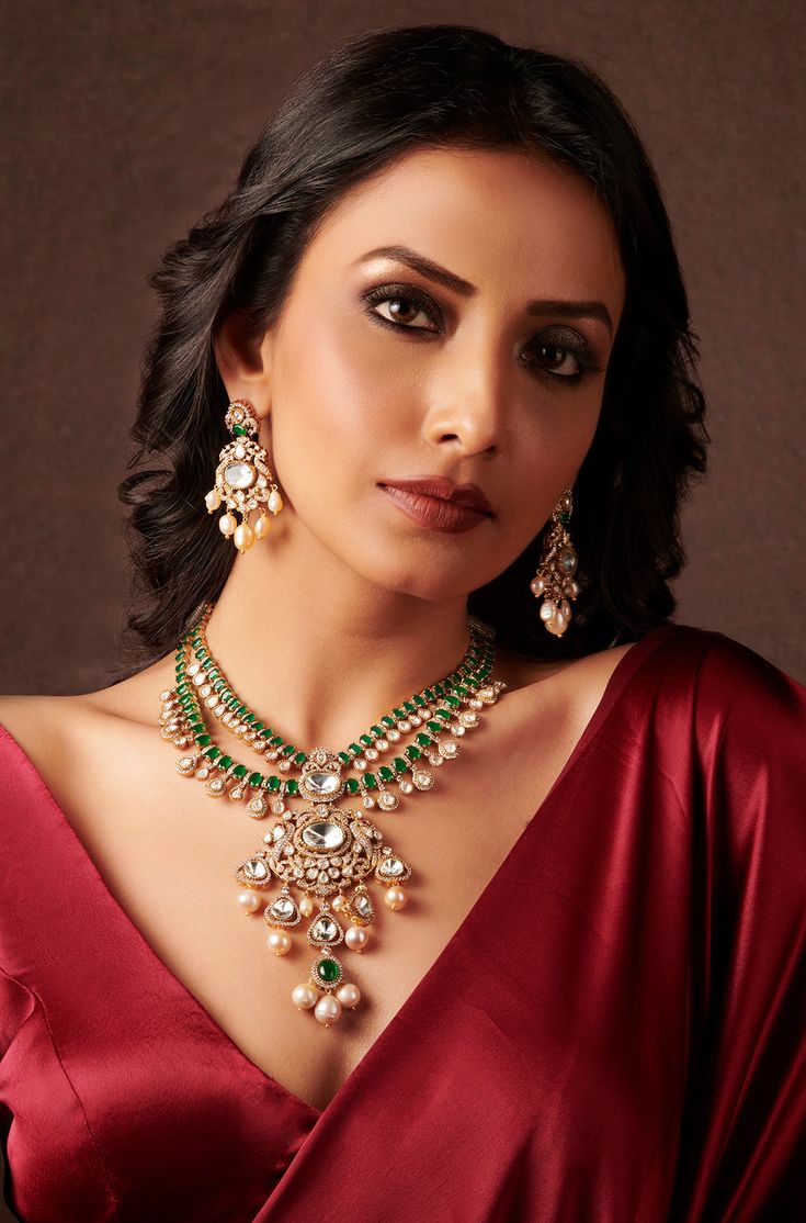 Unveil timeless elegance with this Layered Green Pendant Necklace Set, crafted with precision and style. The set is made from durable brass with a lustrous yellow gold finish, featuring a cascade of layers that exude sophistication. At its heart is a striking green emerald pendant, framed by sparkling Polki stones for an added touch of glamour. Delicate pearls are interspersed throughout, lending a classic, refined feel to the design. The vibrant green hues are balanced by the warm gold and the Polki Emerald Necklaces, Polki Pendant Set, Emerald Necklace Set, Baroque Jewelry, Hand Jewelry Rings, Green Pendant Necklace, Antique Necklaces Design, Antique Necklaces, Pearl Drop Necklace