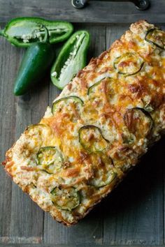 a loaf of bread with zucchini and cheese on it next to green peppers