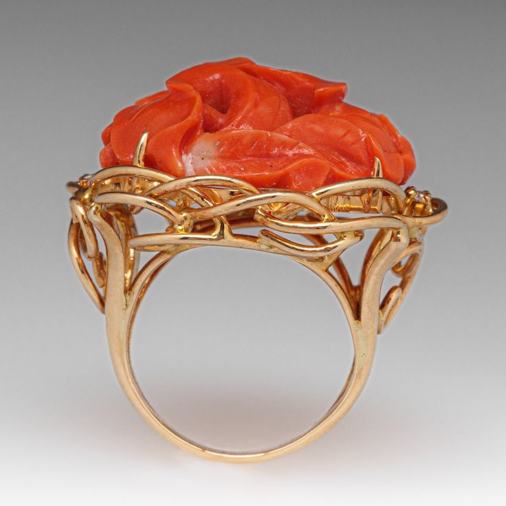 This fantastic vintage ring is centered with a carved floral design coral that is set into four-prongs. The coral is bordered with four (4) prong set round brilliant cut diamonds. The ring measures 25.9mm at the top, rises 12.7mm above the finger, tapering to 2.5mm wide and 0.8mm thick at the base of the shank. It is currently a size 4.5. Elegant Coral Rings For Anniversary, Elegant Carved Orange Jewelry, Elegant Orange Carved Jewelry, Elegant Coral Ring Jewelry, Coral Elegant Wedding Rings, Elegant Coral Wedding Rings, Coral Ring, Mid Century Jewelry, The Coral