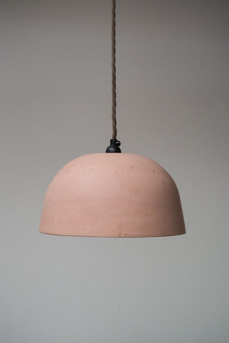 a light that is hanging from a rope on the ceiling with a gray wall in the background