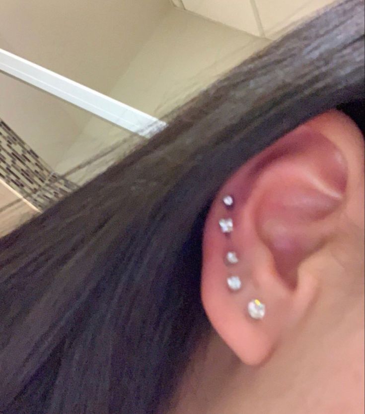 a woman's ear with three piercings on it