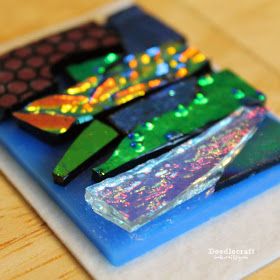 three pieces of colorful glass sitting on top of a wooden table next to each other