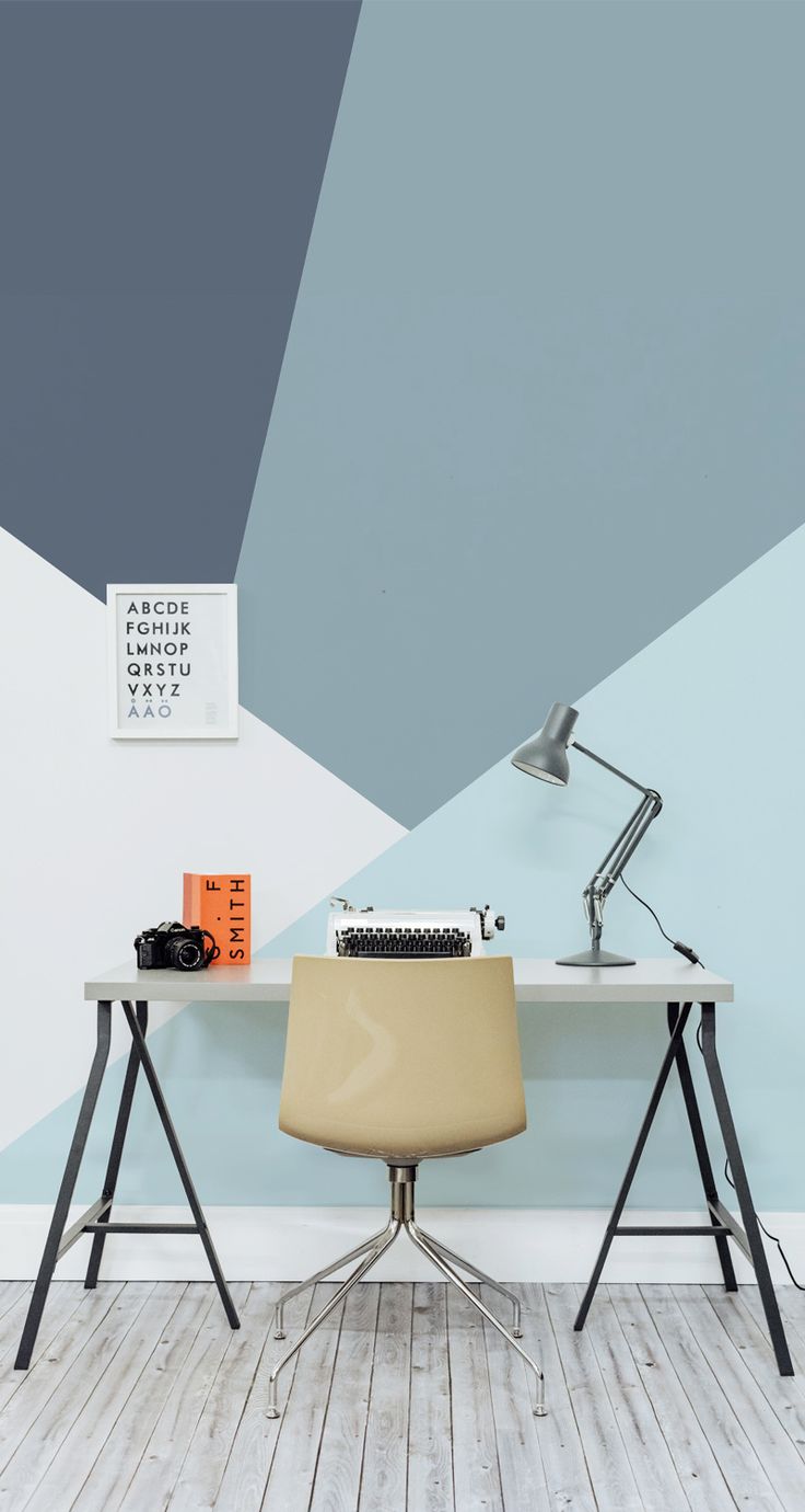 a desk with a chair and a lamp on it in front of a blue wall