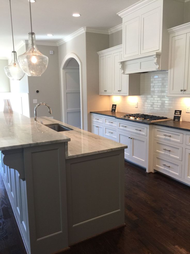 a large kitchen with white cabinets and an island in the middle of the room is lit by two pendant lights