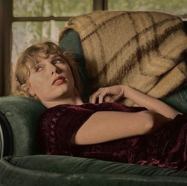 a woman laying on top of a green couch