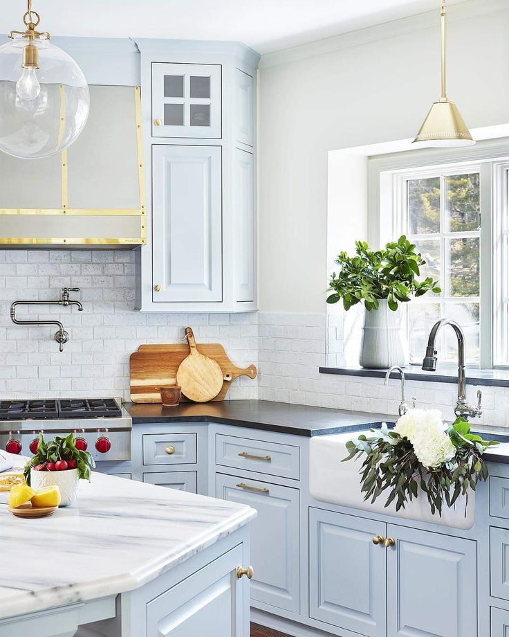 a kitchen with blue cabinets and white marble counter tops, an island in the middle