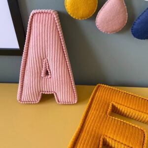 the letter e is made out of felt and sits next to three other pieces of fabric