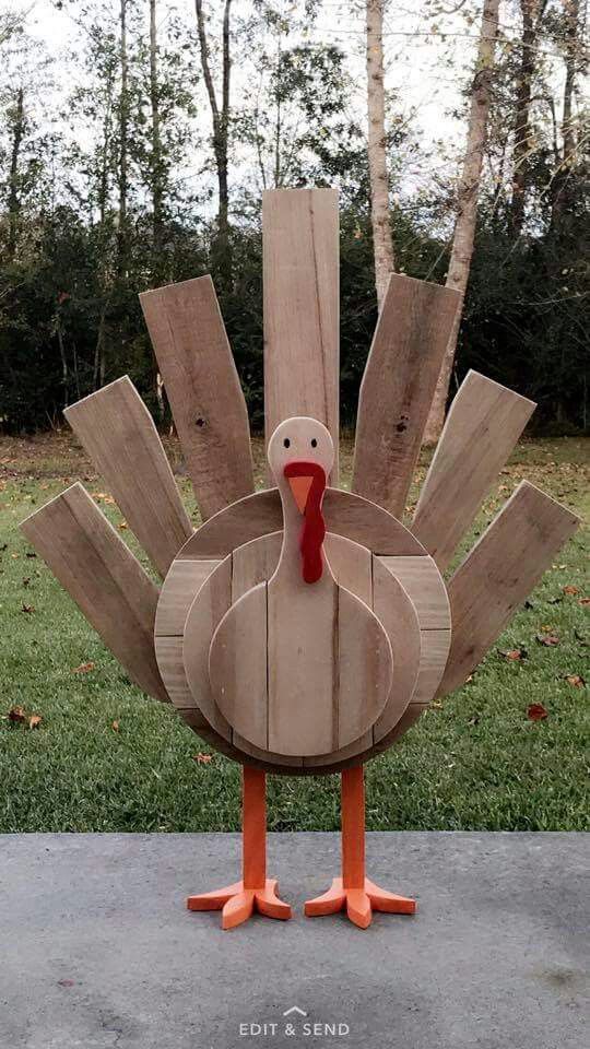 a large wooden turkey standing on top of a cement slab in front of some trees