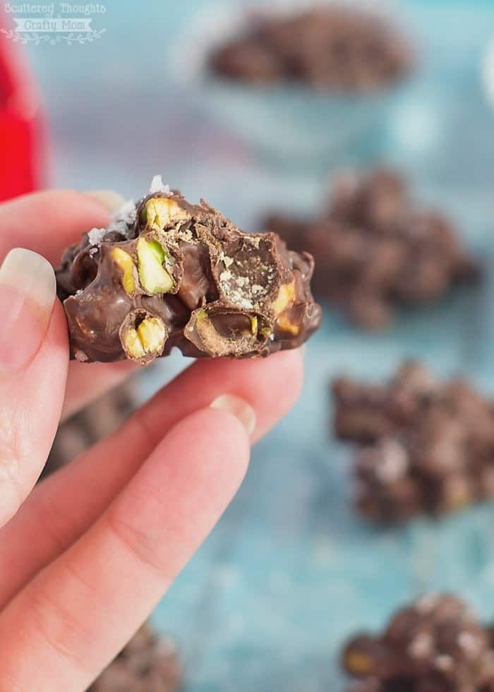 a hand holding a half eaten chocolate and nuts snack in it's left hand