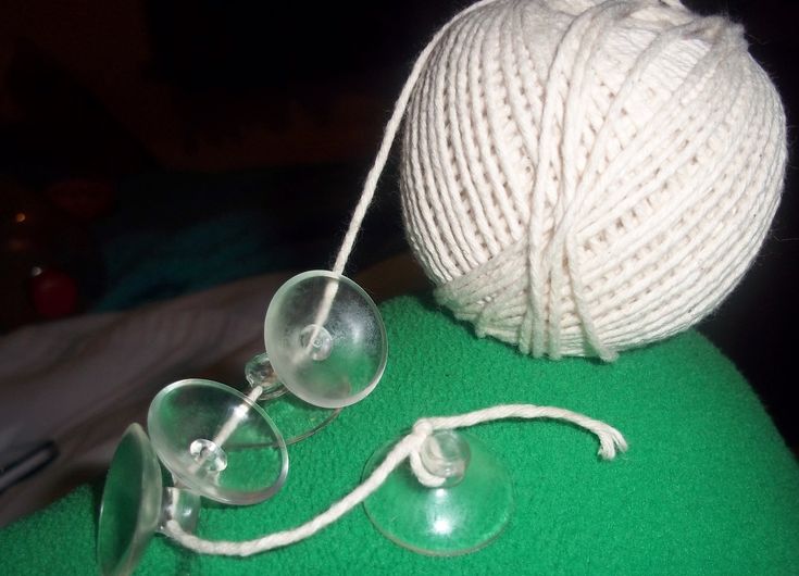 a ball of yarn and two glasses on a green surface with a white string attached to it