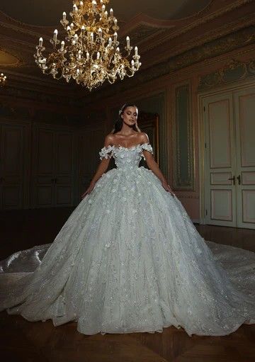 a woman in a white wedding dress standing next to a chandelier with lights on it